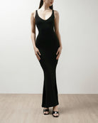 Woman wearing a black shapewear dress against a plain background.