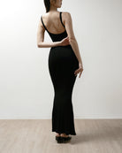 Woman wearing a black shapewear dress against a white background.