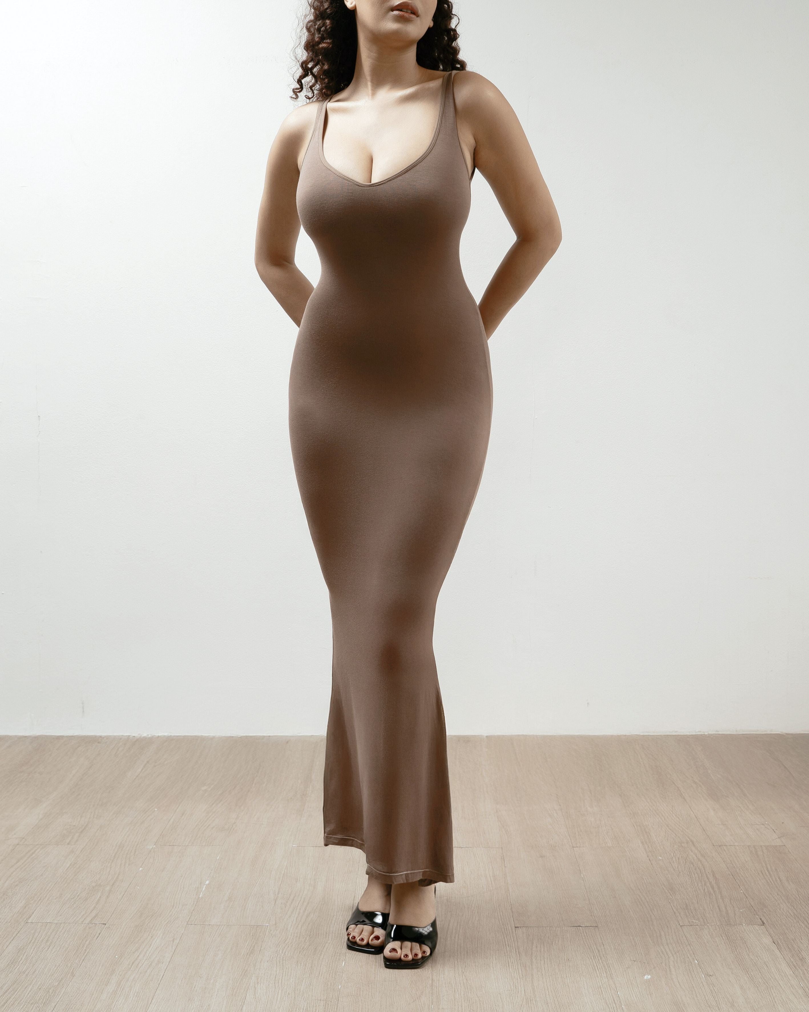 Woman wearing a brown shapewear dress against a white background.
