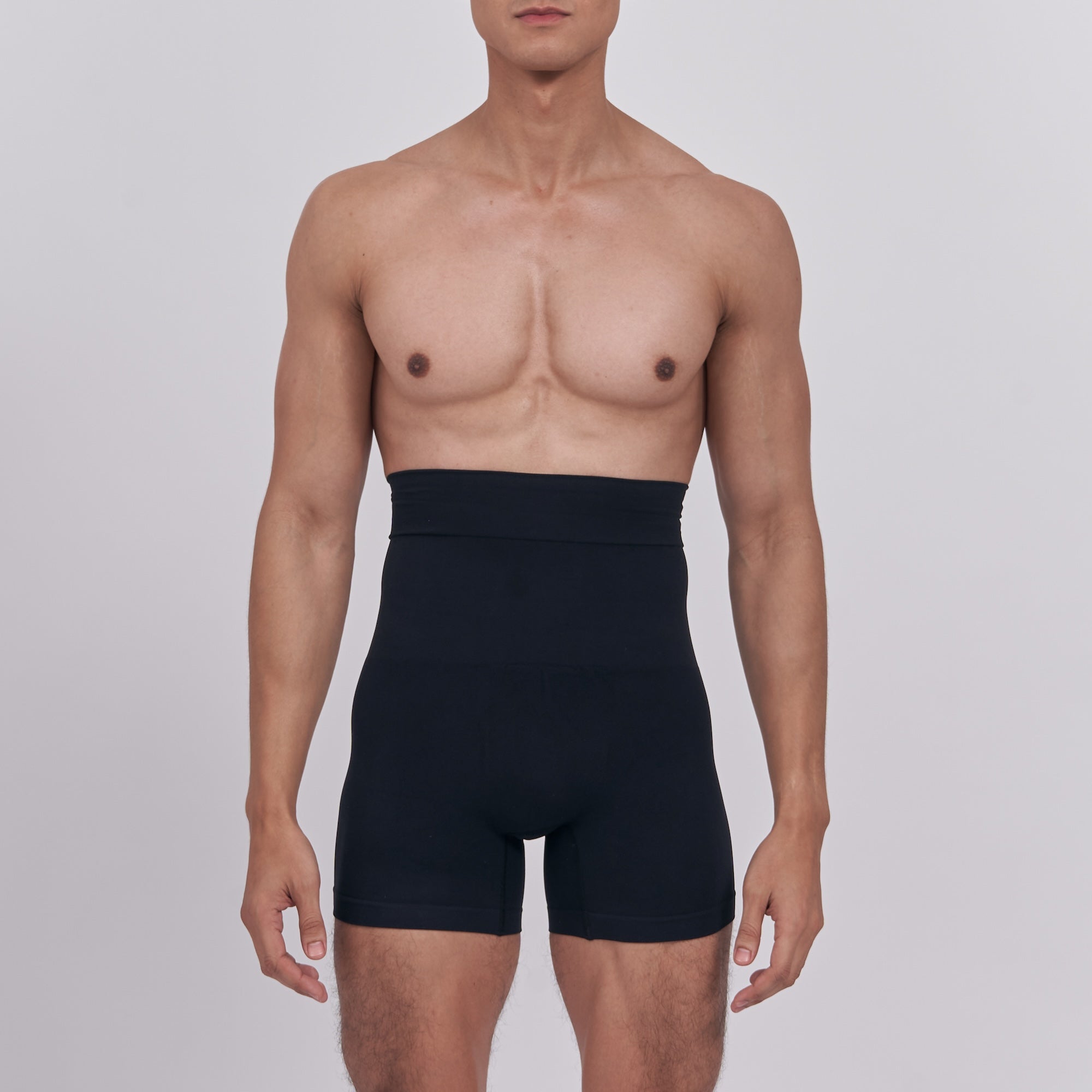 Man wearing a black waist trainer against a plain background
