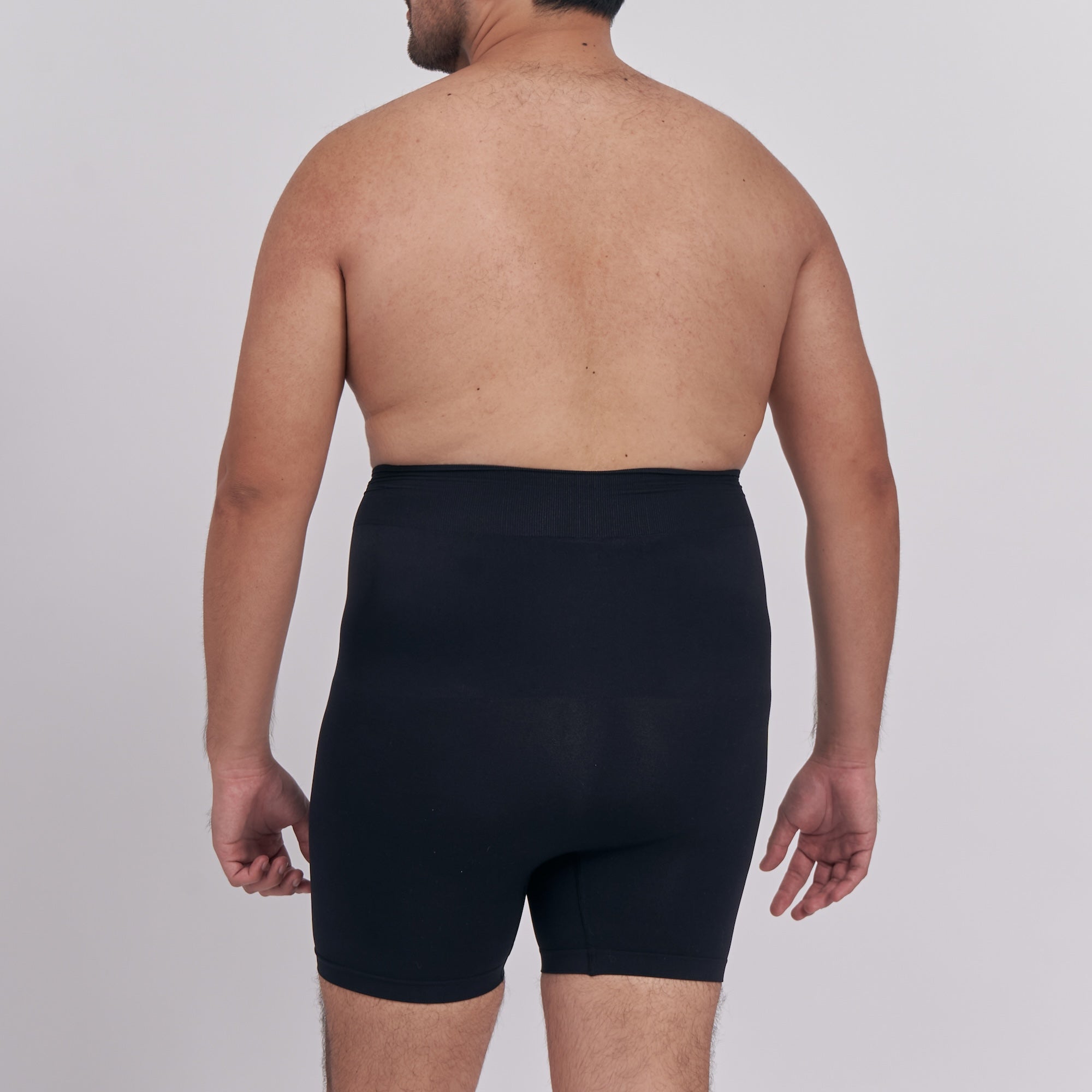 Man wearing black underwear on a plain background