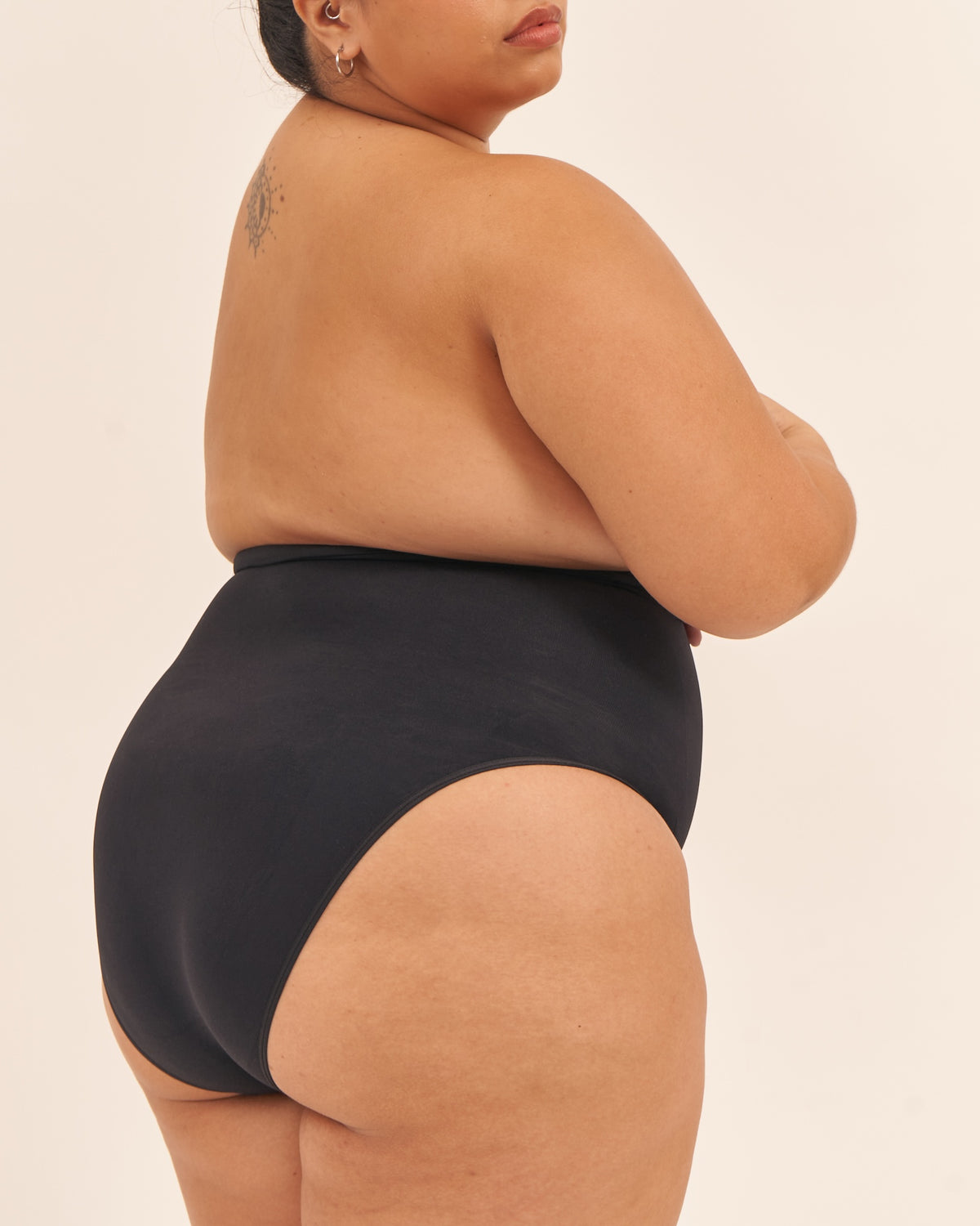 Person wearing a black swimsuit on a beige background