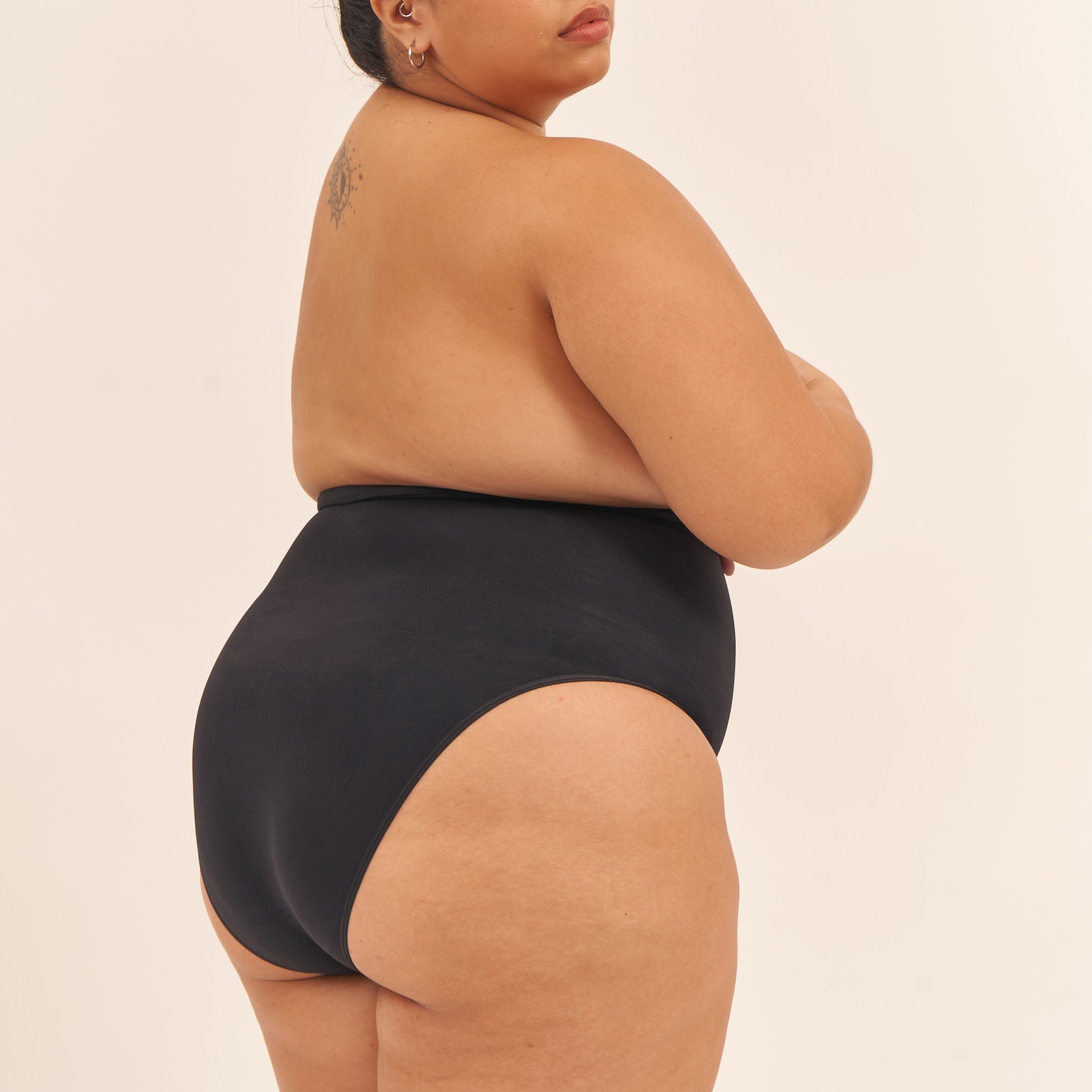 Person wearing a black swimsuit on a beige background