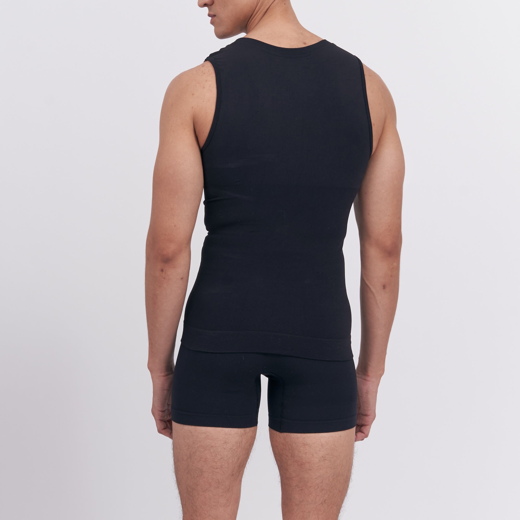 Person wearing a black sleeveless top and shorts on a light gray background