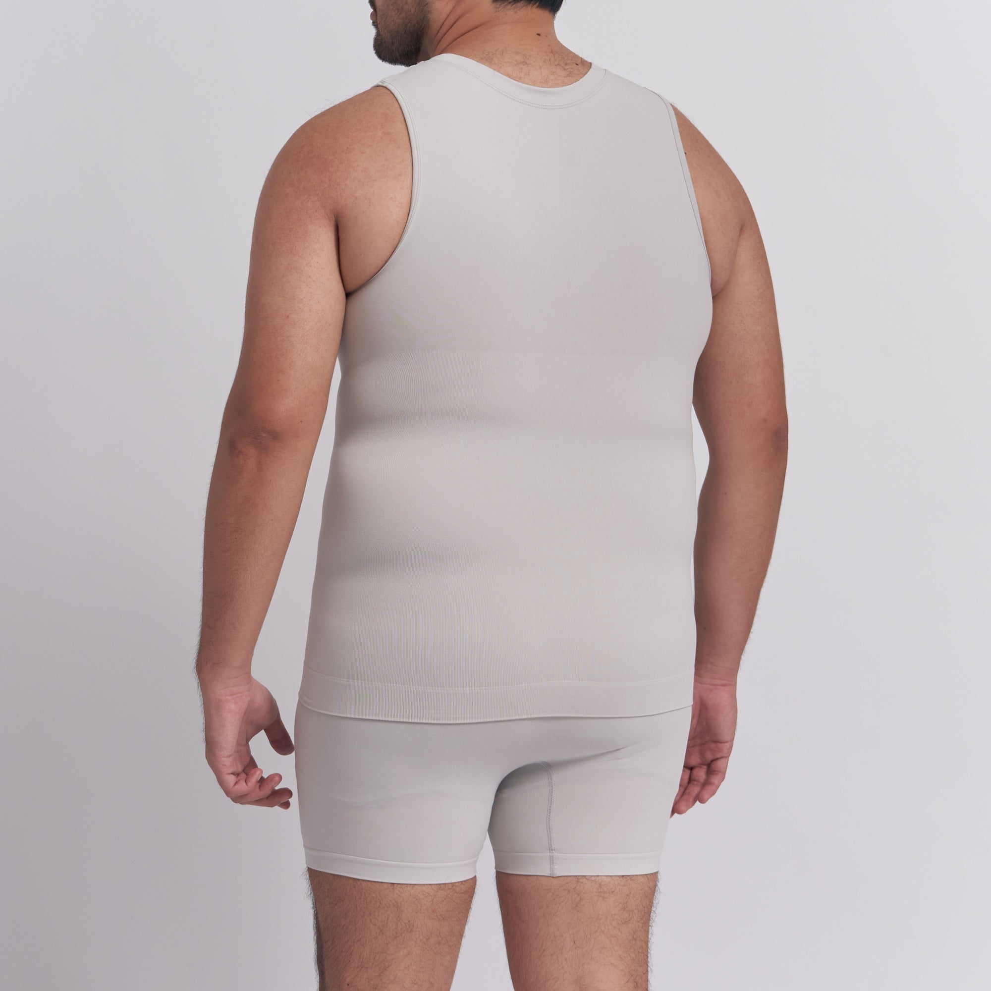 Person wearing a beige tank top and shorts set on a plain background