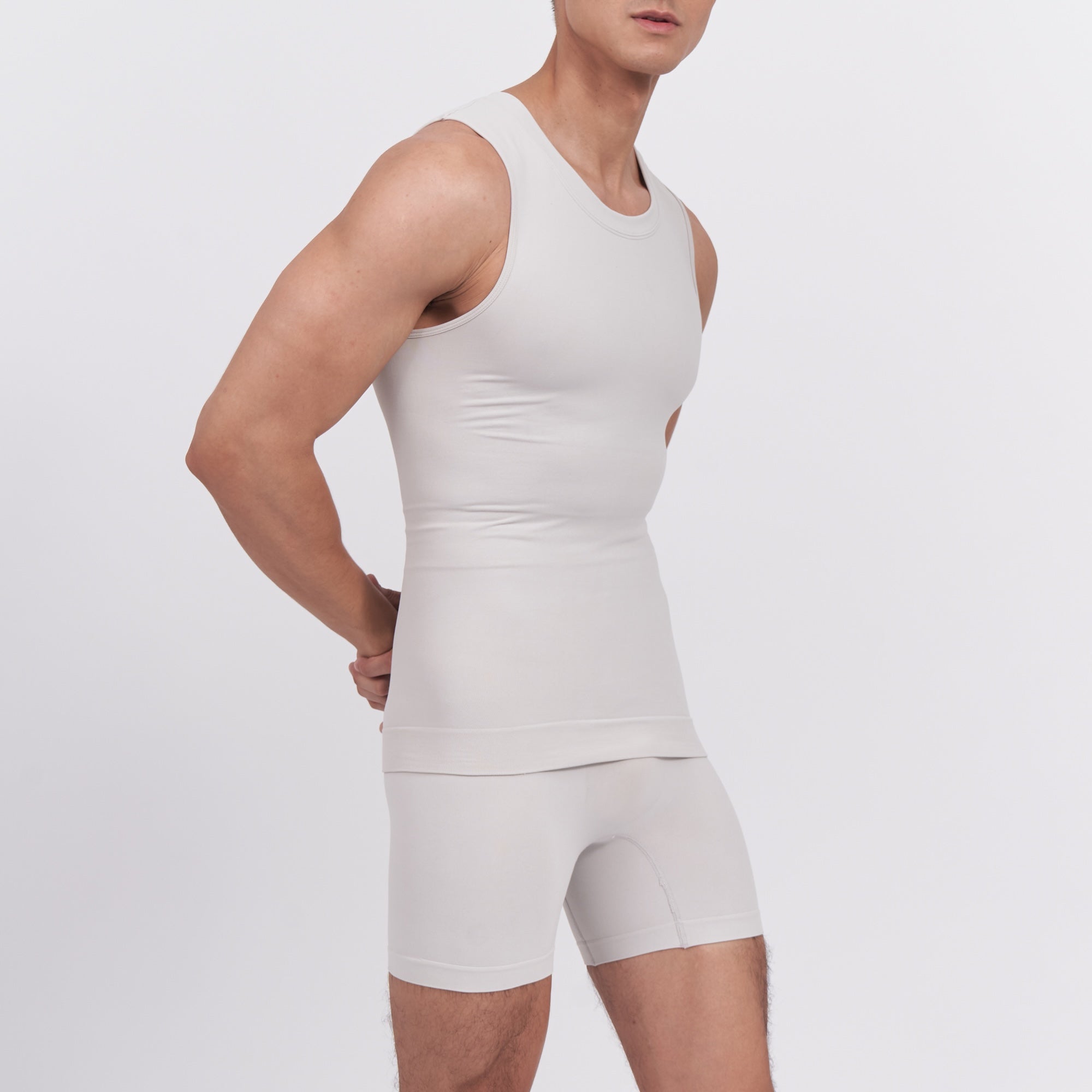 Person wearing a white tank top and shorts set on a light gray background