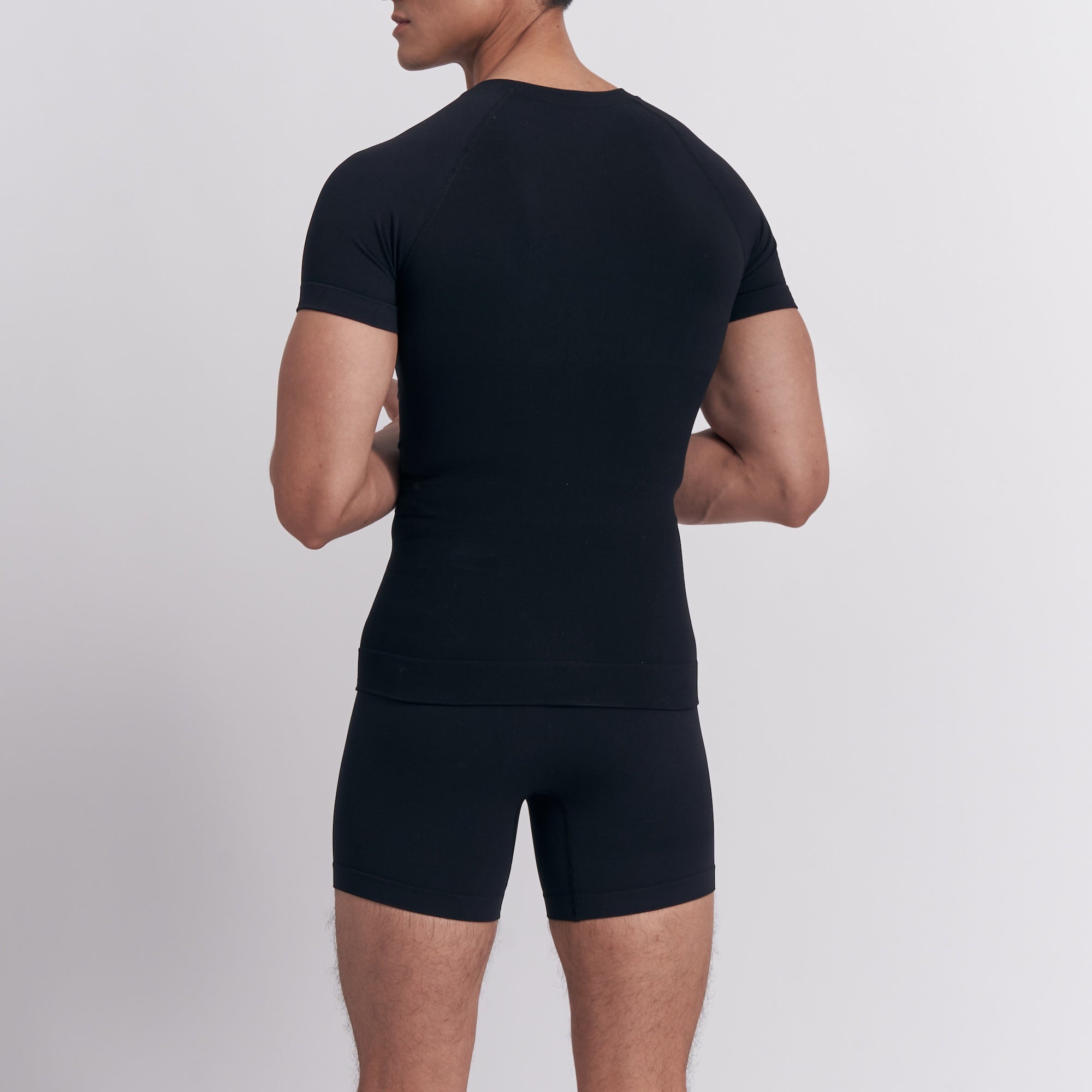 Person wearing a black t-shirt and shorts set on a light gray background