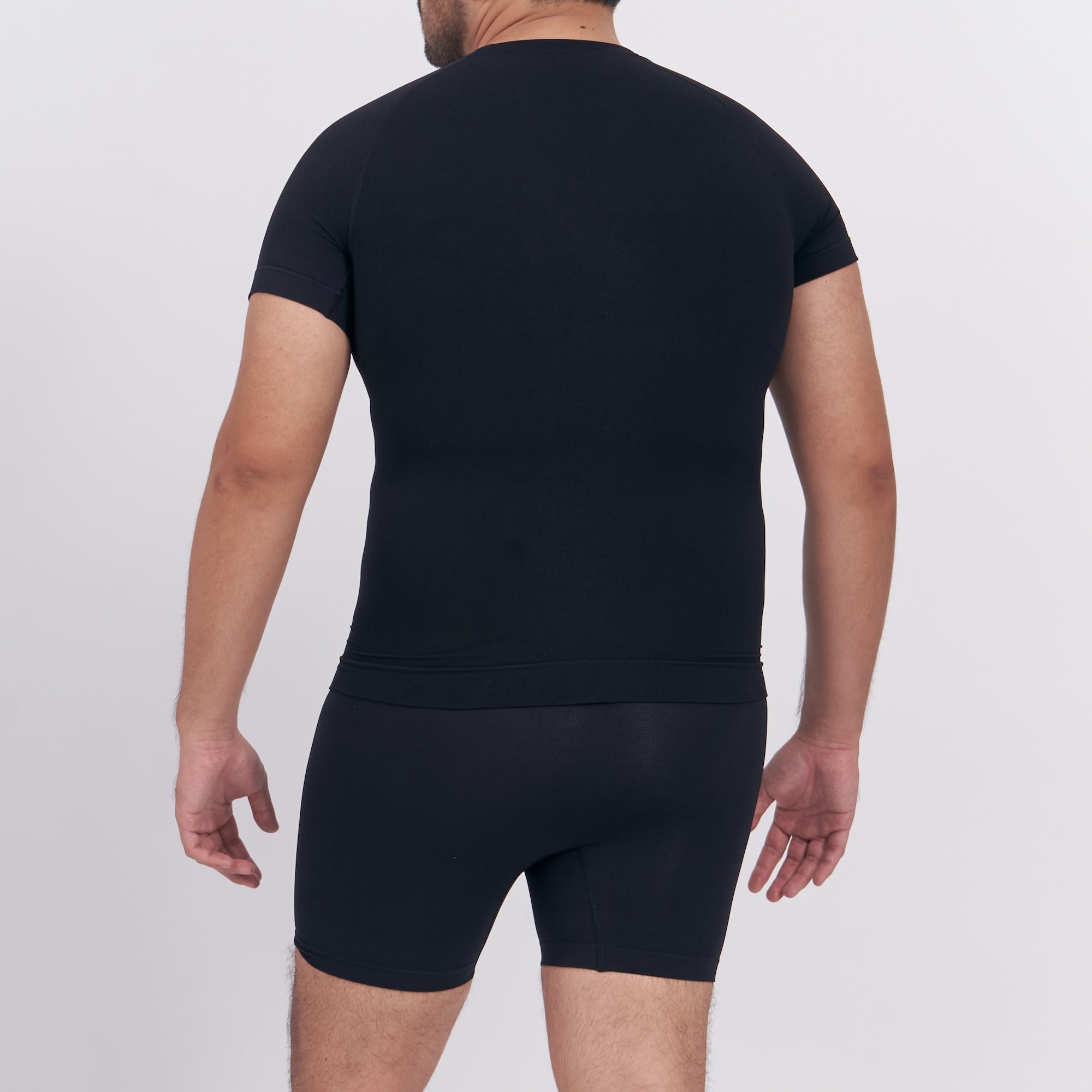 Person wearing a black t-shirt and black underwear on a white background