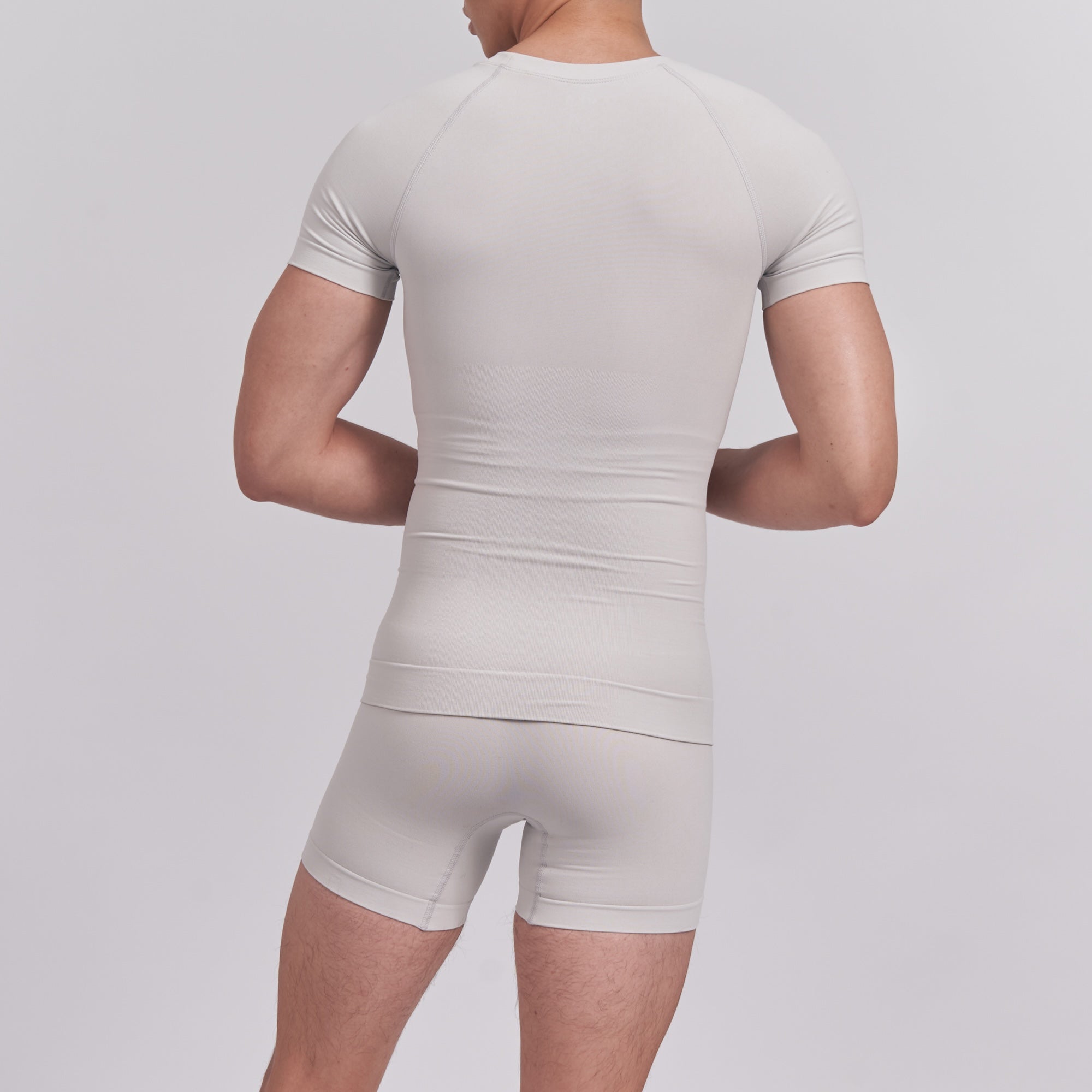 Person wearing a beige bodysuit against a light gray background
