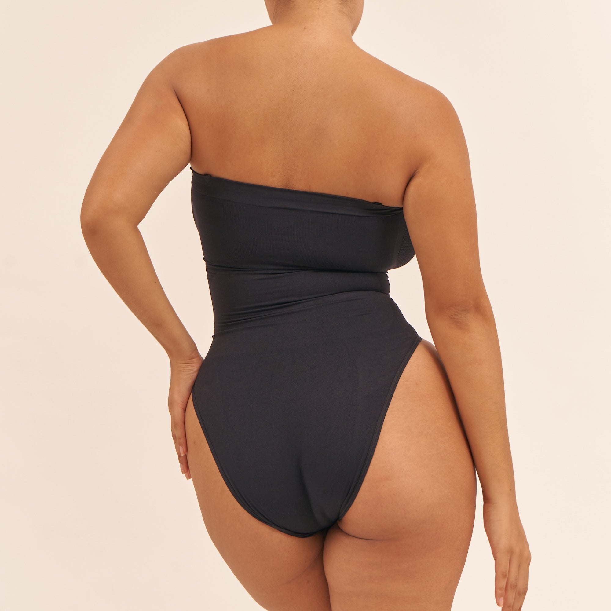 Black strapless swimsuit with high cut design on a beige background