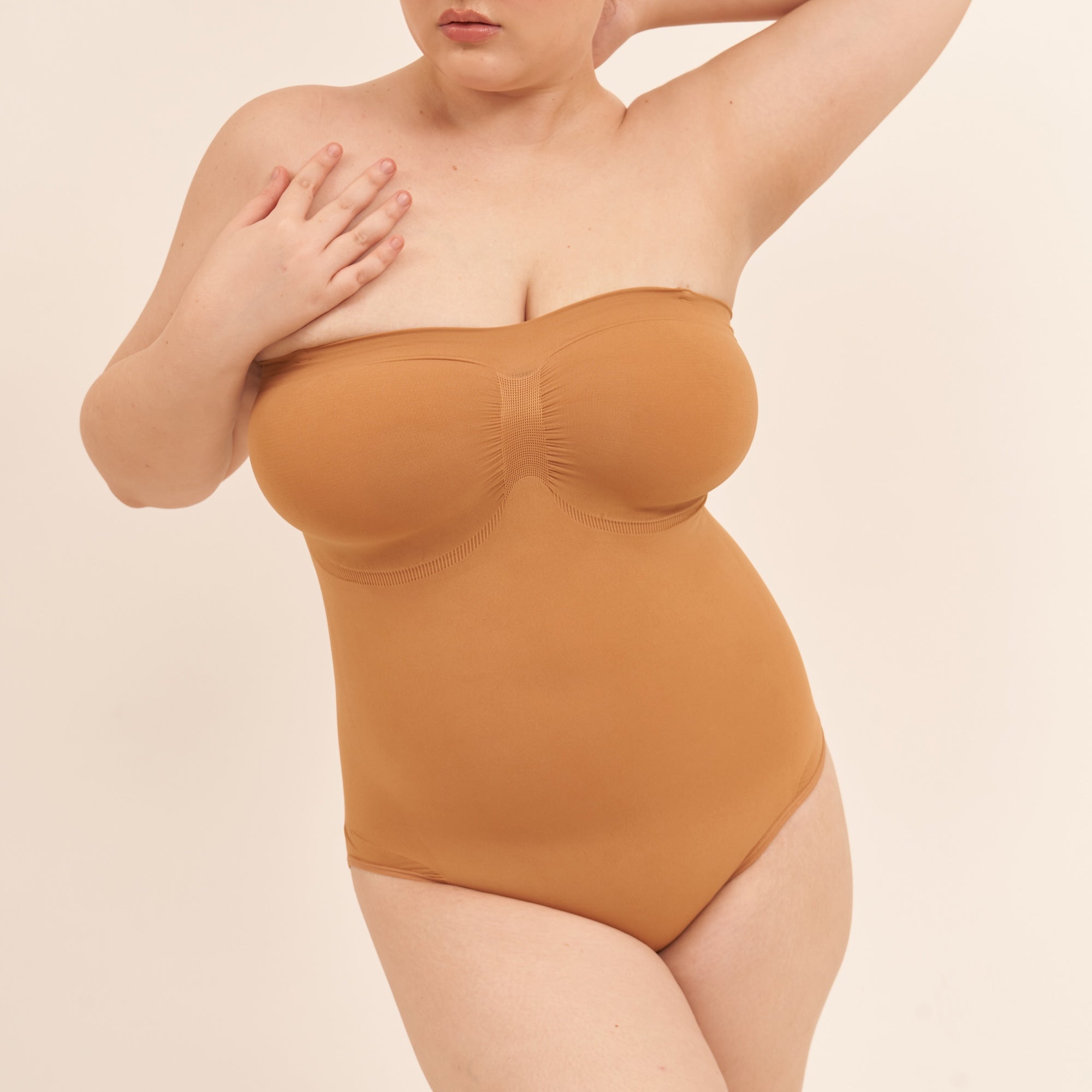 Person wearing a brown strapless bodysuit on a beige background