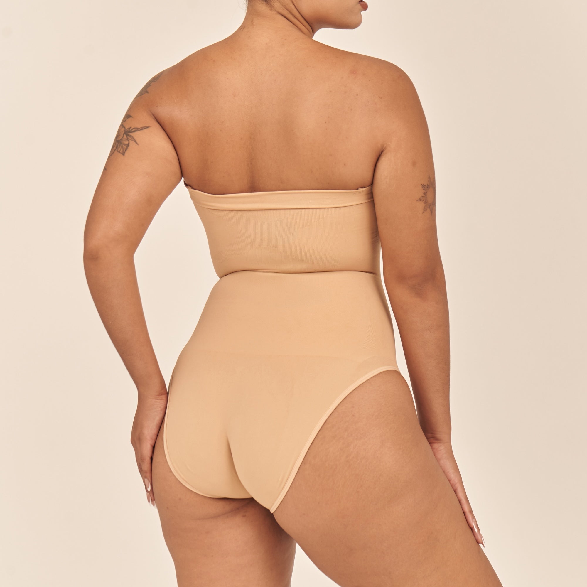 Beige swimsuit worn by a model on a beige background
