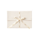Beige envelope with a bow and 'SOLA' ribbon on a white background