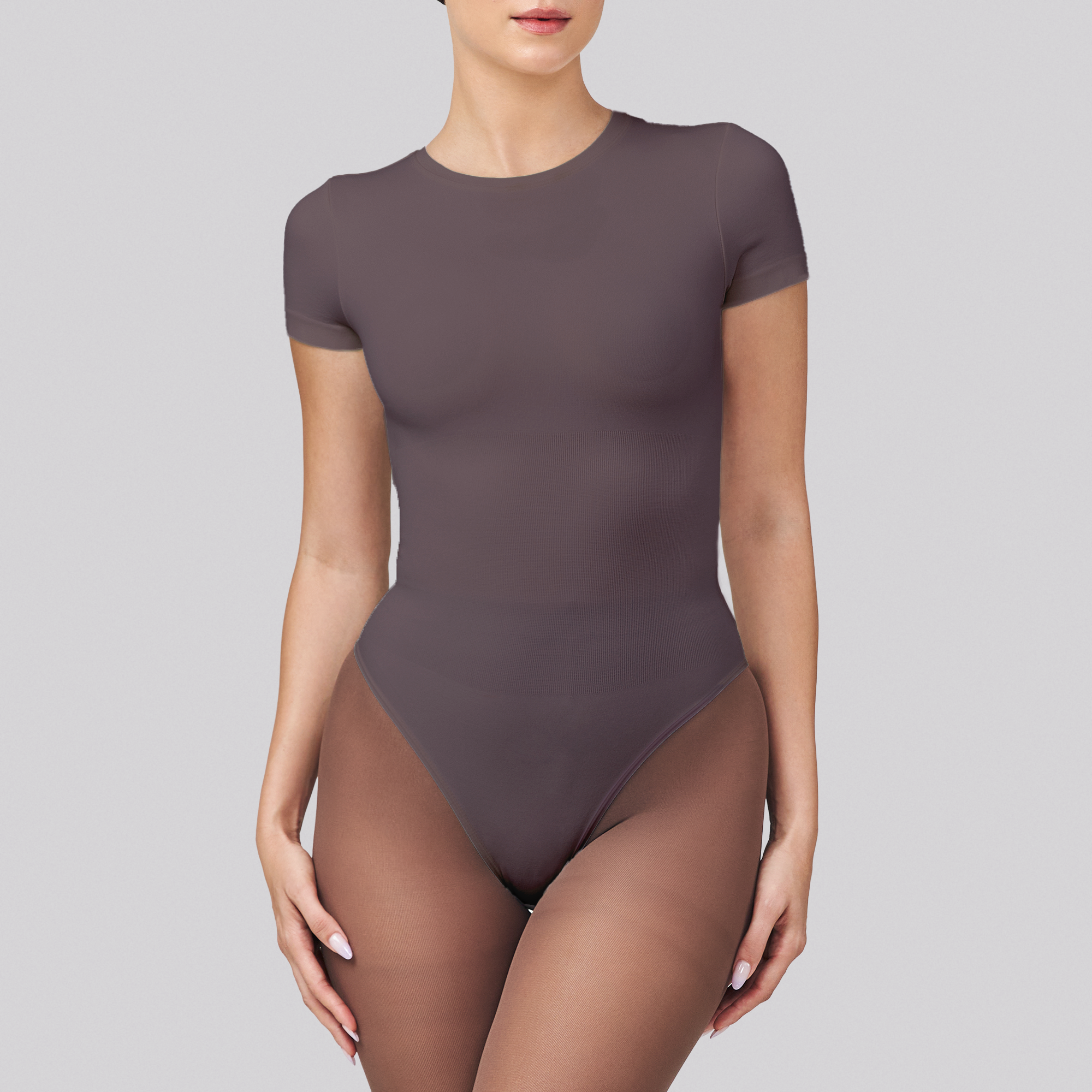 Person wearing a dark gray bodysuit on a light gray background