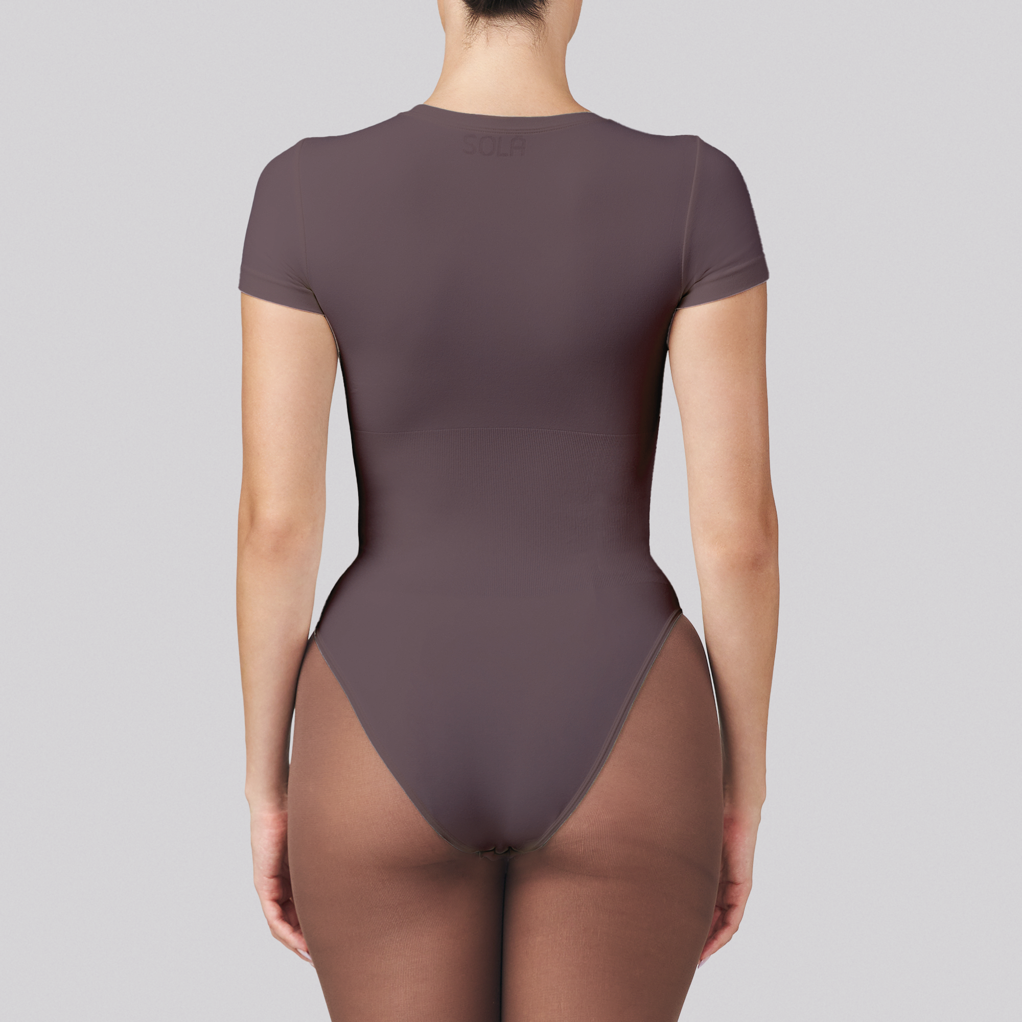 Brown bodysuit worn by a model on a gray background
