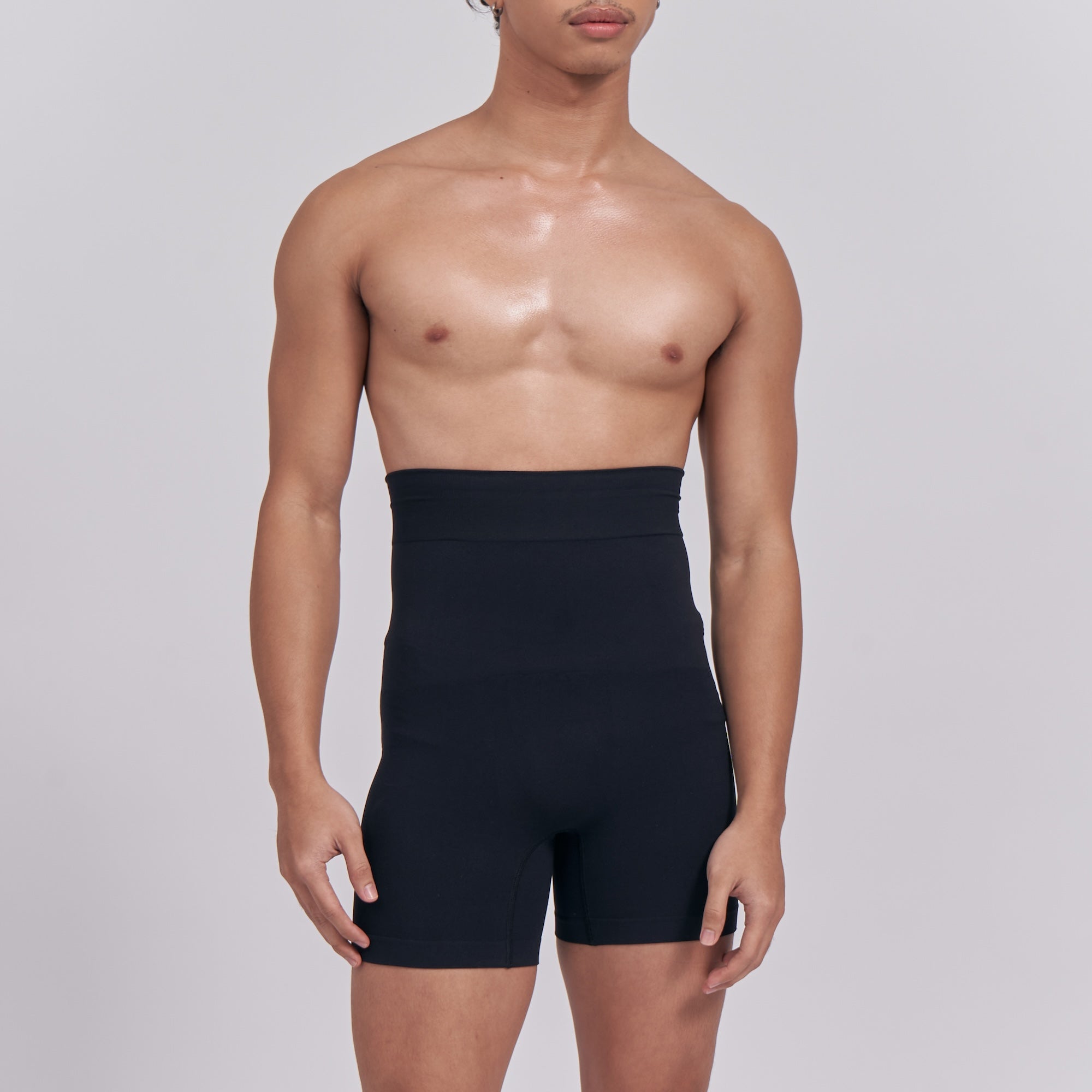Person wearing a black high-waisted shapewear garment on a plain background