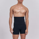 Person wearing a black high-waisted shapewear garment on a plain background