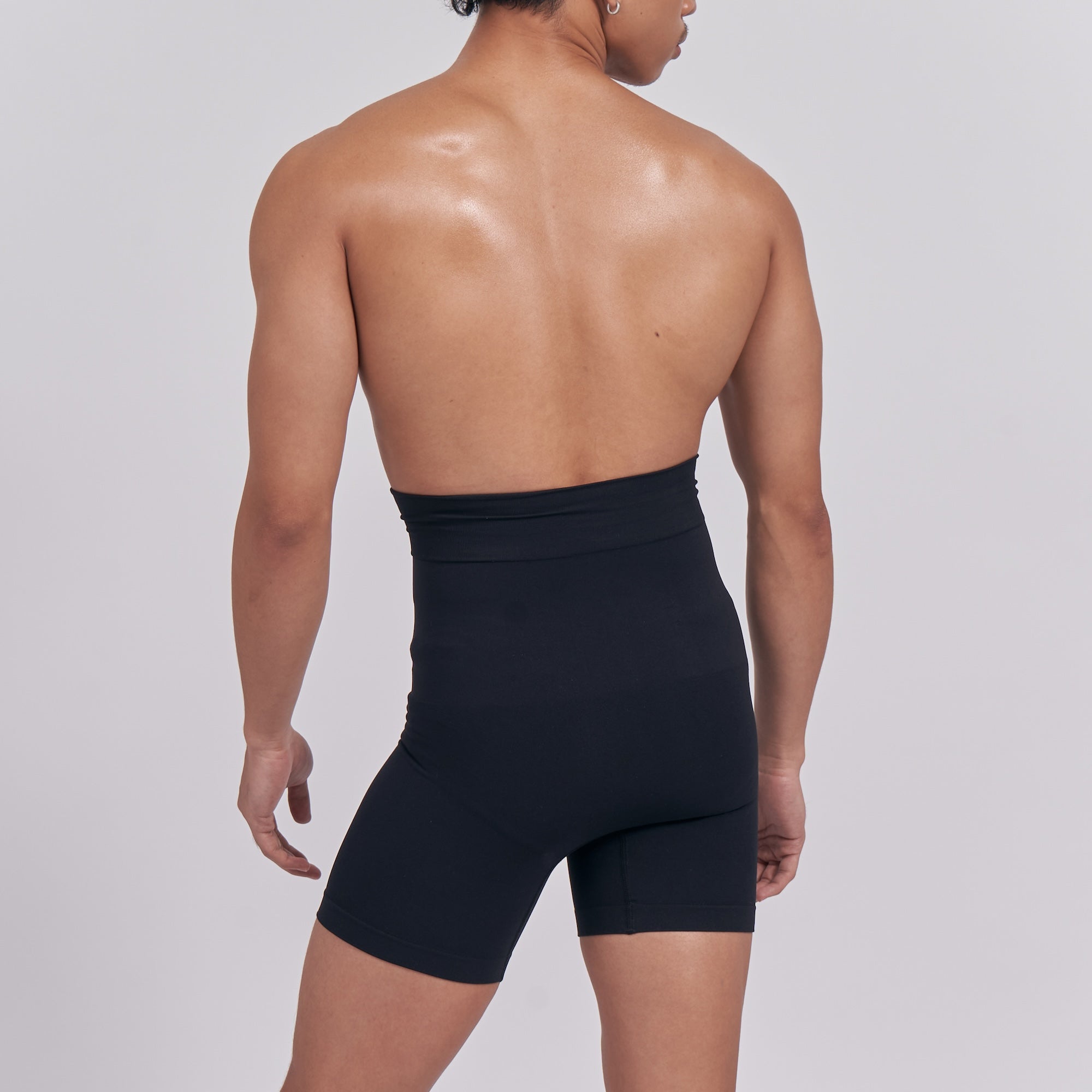 Person wearing a black shapewear garment on a plain background