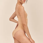 Beige bodysuit worn by a model on a beige background