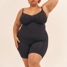 Person wearing a black bodysuit against a beige background