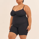 Person wearing a black bodysuit against a beige background