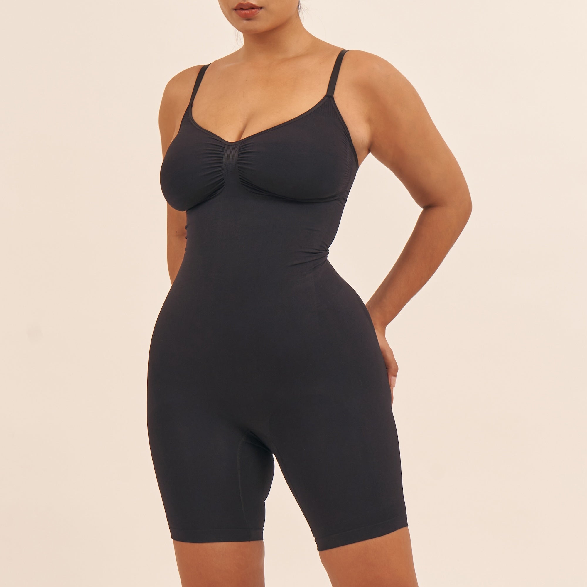 Black bodysuit worn by a model on a beige background