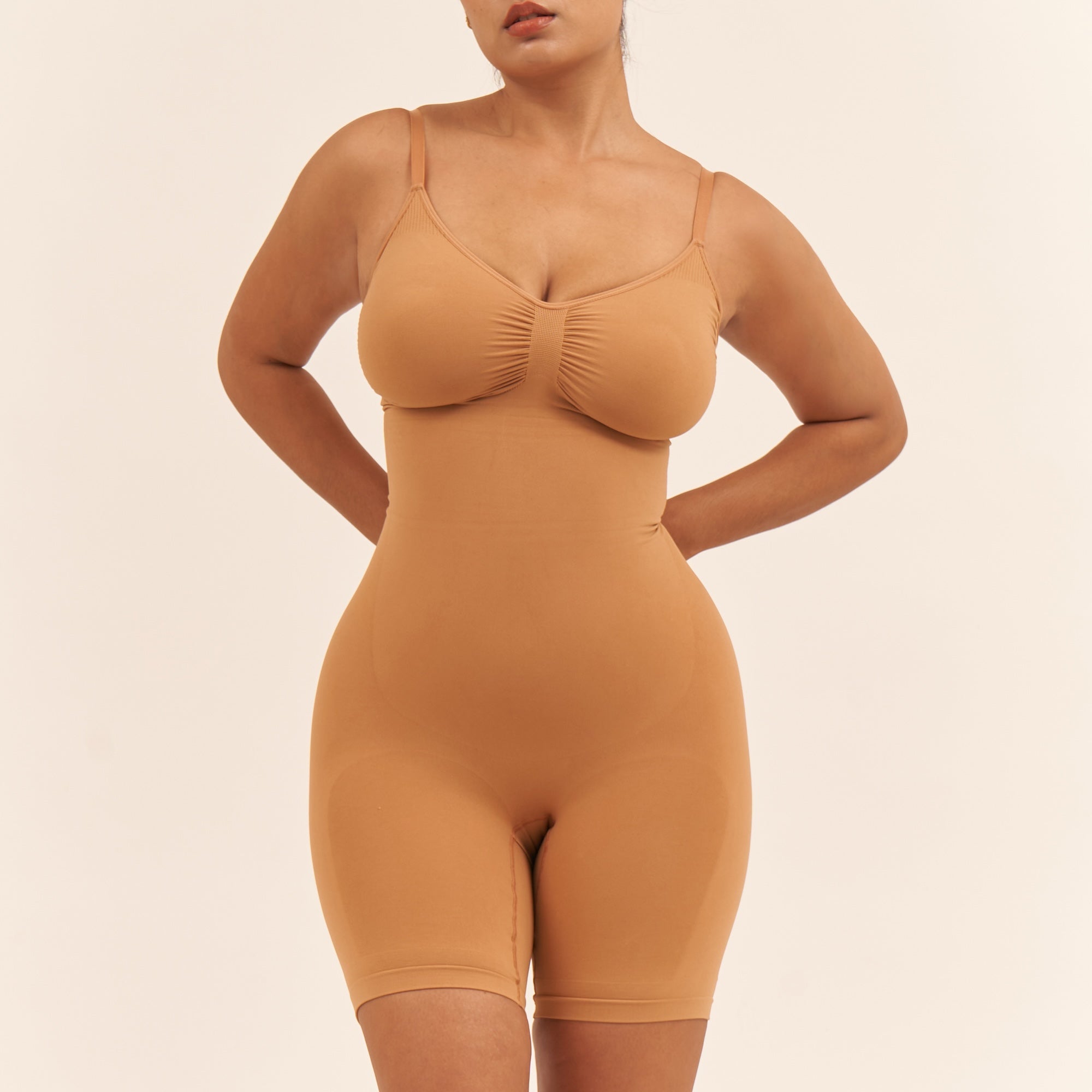 Woman wearing a beige shapewear bodysuit against a beige background