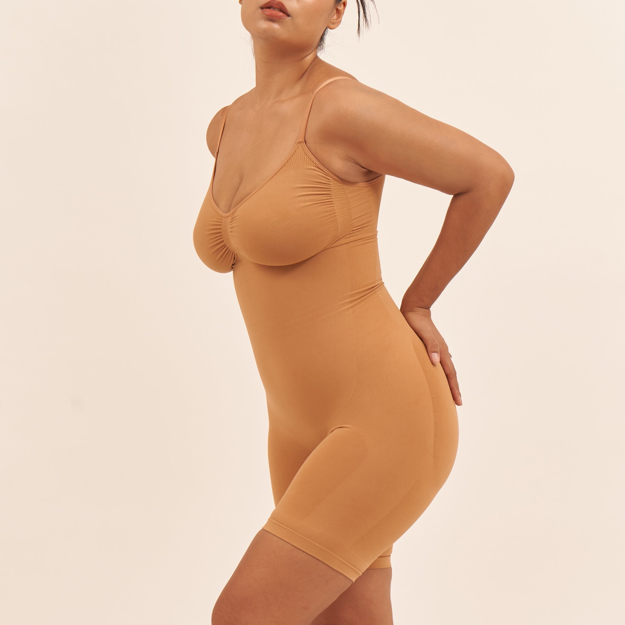 Woman wearing a mustard yellow bodysuit against a beige background