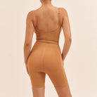 Person wearing a brown bodysuit on a beige background