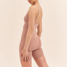 Woman wearing a beige shapewear garment on a beige background