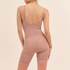 Person wearing a pink bodysuit against a beige background
