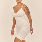 Woman wearing a white slip dress against a beige background