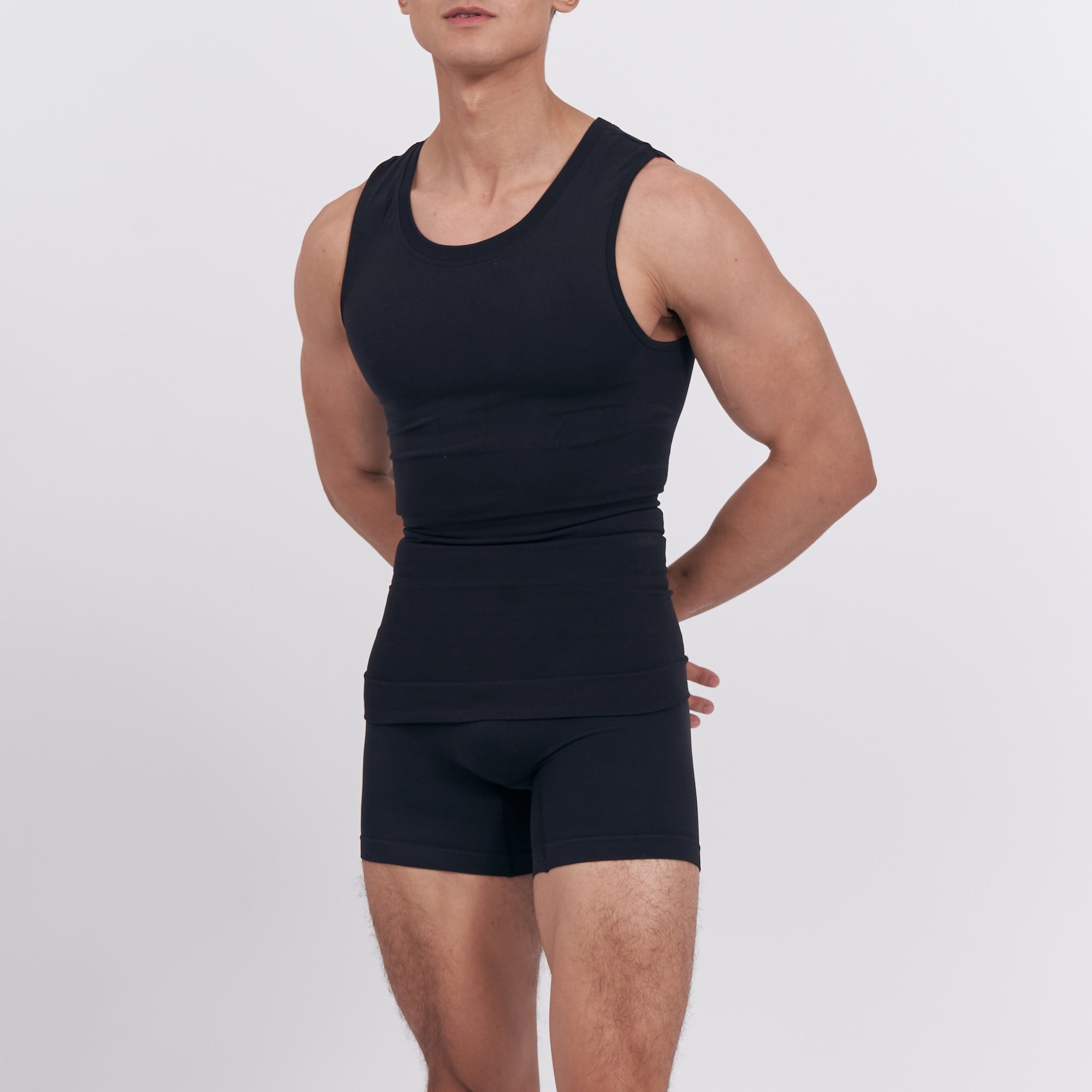 Person wearing a black tank top and shorts on a light gray background