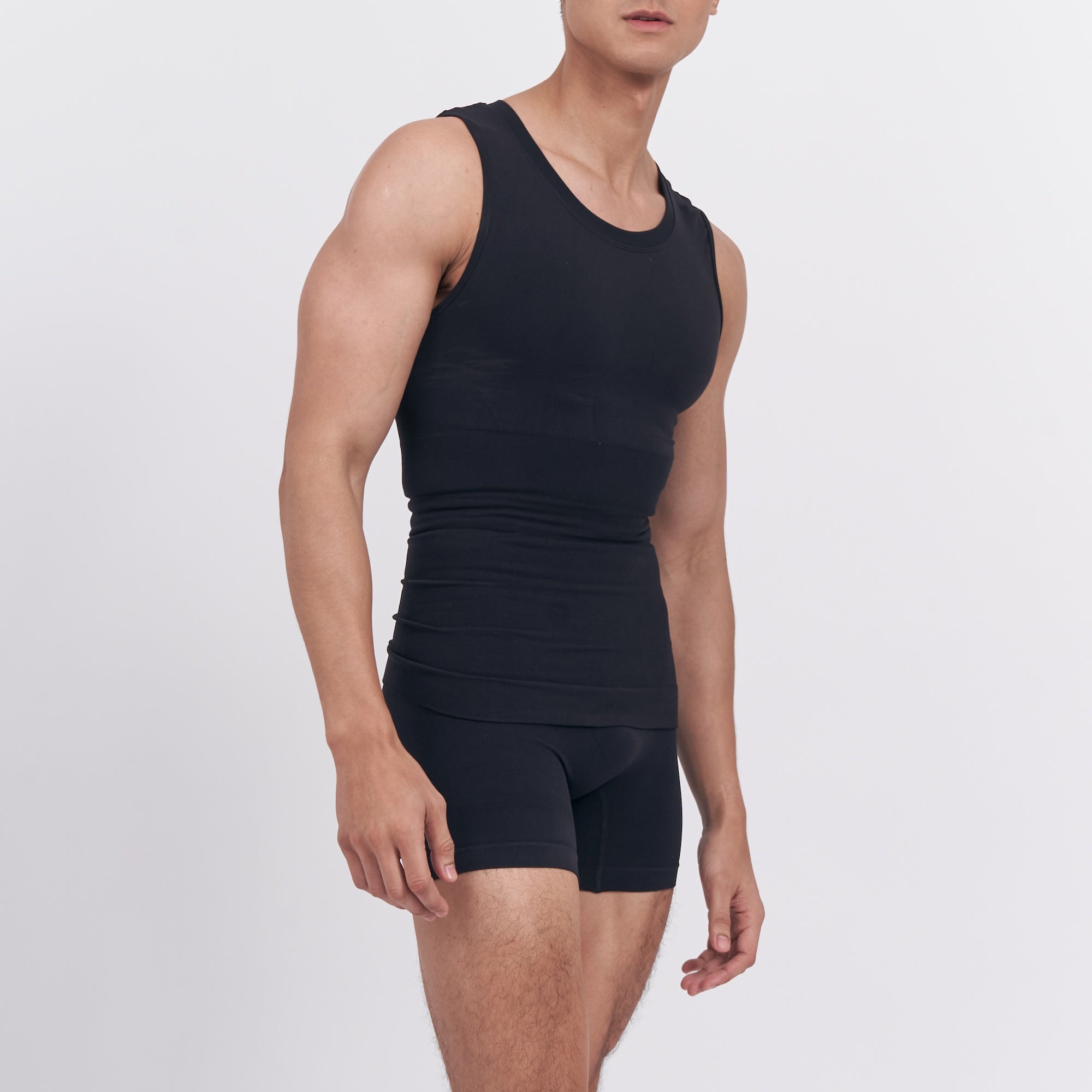 Person wearing a black tank top and shorts on a white background