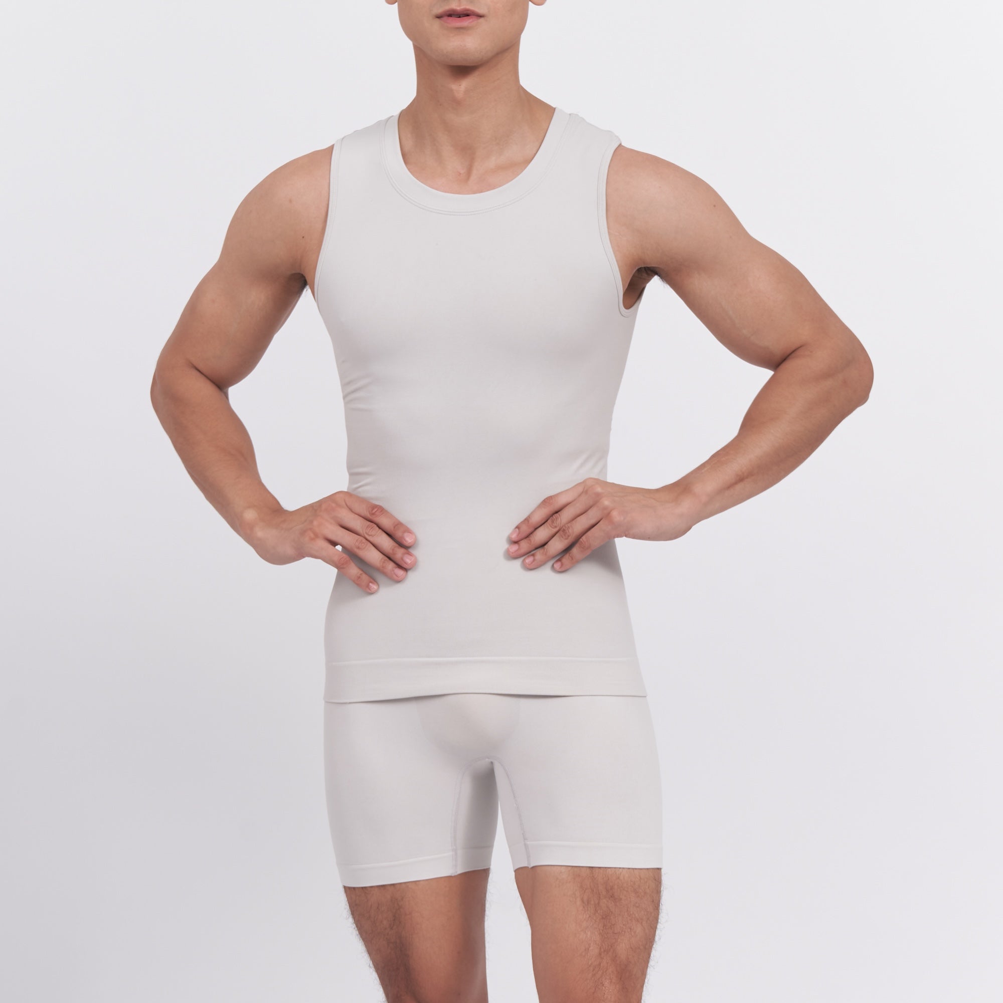 Person wearing a white tank top and shorts set on a plain background