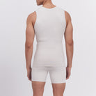 Person wearing a white tank top and shorts on a light gray background