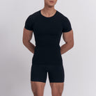 Person wearing a black compression shirt and shorts set on a light gray background