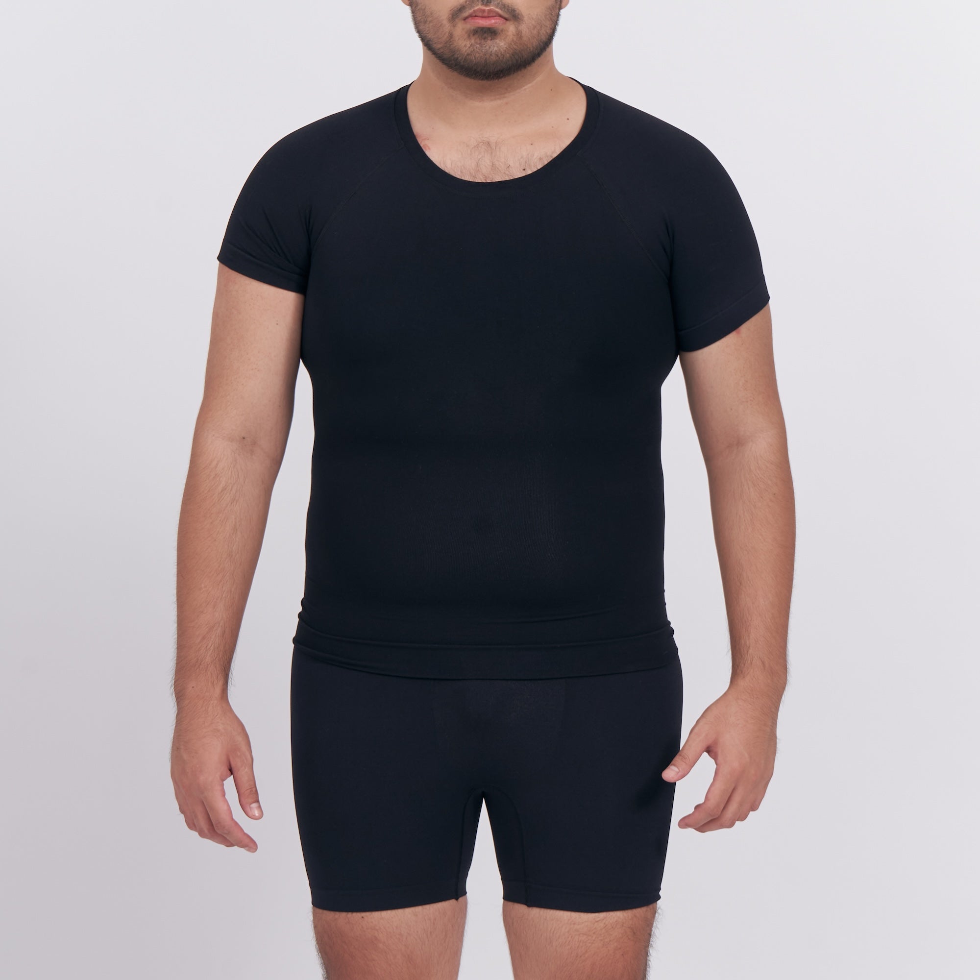 Person wearing a black t-shirt and black shorts on a white background