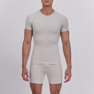 Man wearing a beige compression shirt and shorts set on a light gray background