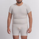 Man wearing a beige compression shirt and shorts set on a light gray background