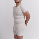 Man wearing a beige compression shirt and shorts set on a light gray background