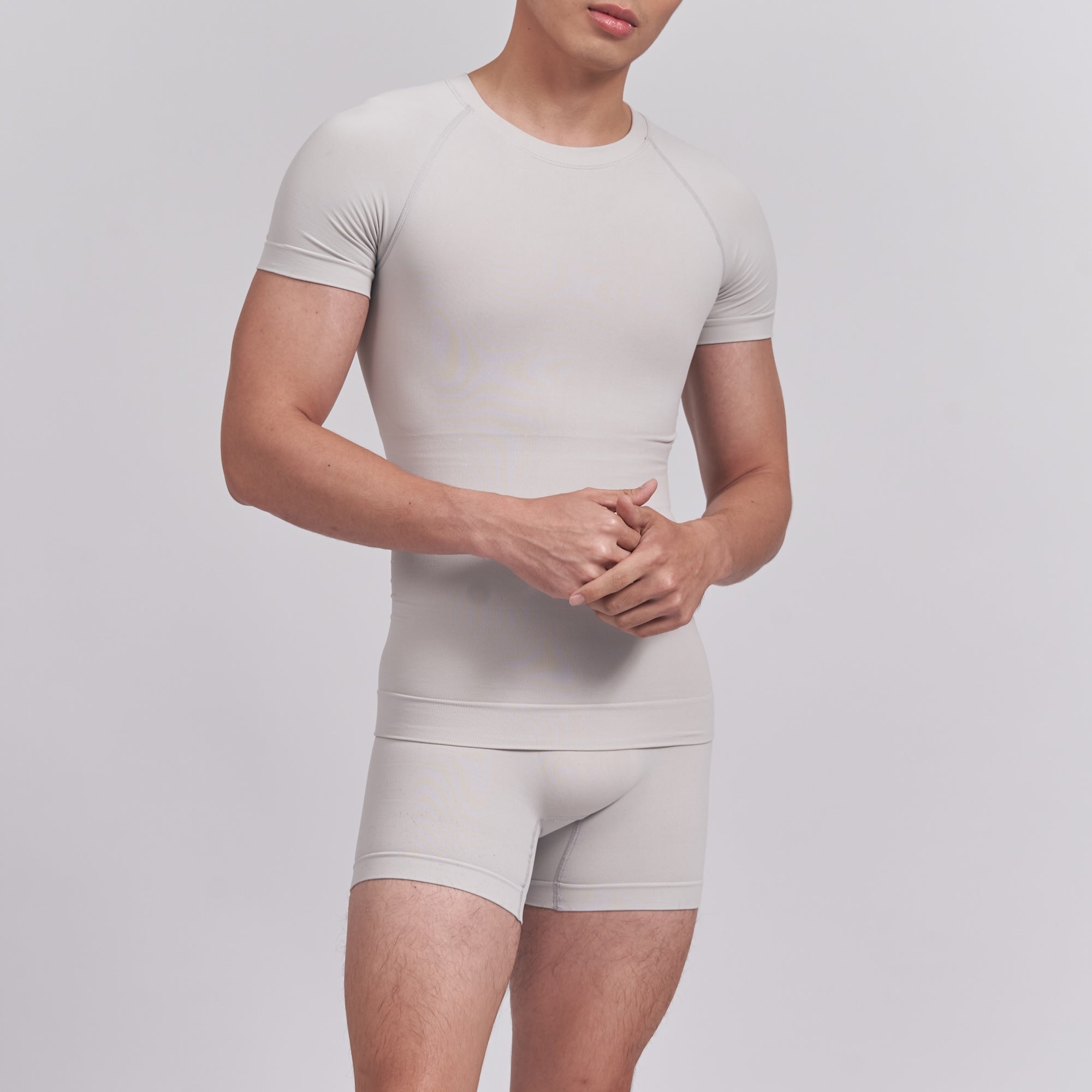 Person wearing a beige t-shirt and shorts set on a light gray background