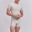 Person wearing a beige t-shirt and shorts set on a light gray background