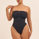 Black strapless swimsuit worn by a model on a beige background