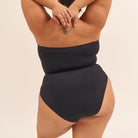Person wearing a black swimsuit on a beige background