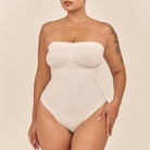 Woman wearing a white strapless swimsuit against a beige background