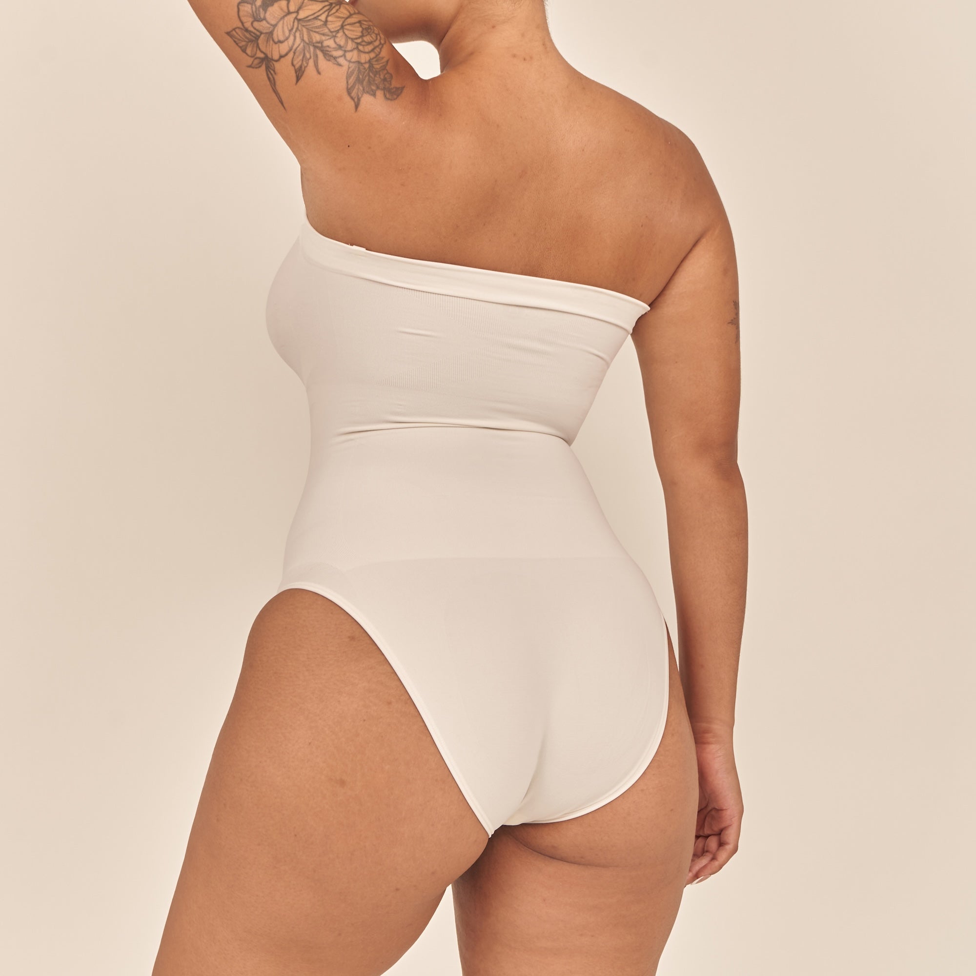 White strapless swimsuit worn by a person on a beige background