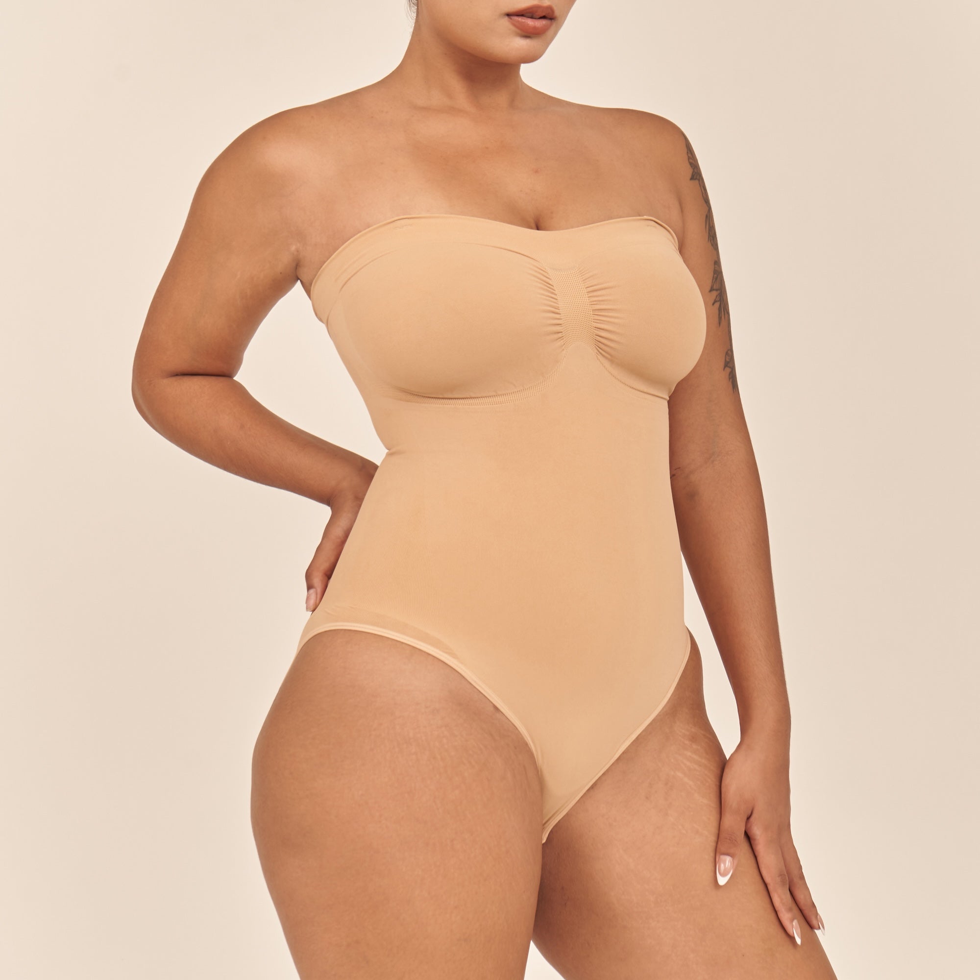 Woman wearing a beige strapless bodysuit against a beige background
