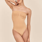 Woman wearing a beige strapless swimsuit against a beige background